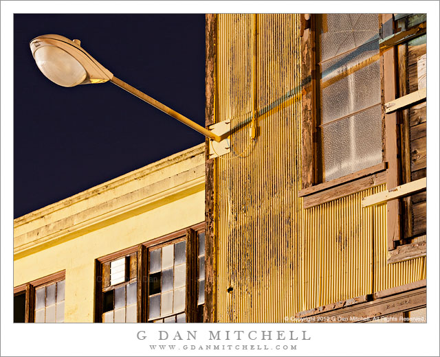 Street Light, Yellow Walls - A street light attached to the exterior of dilapidated industrial buildings at the historic Mare Island Naval Ship Yard.