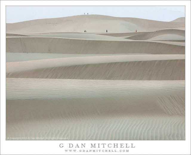 Walkers contemplate evening light on sand dunes