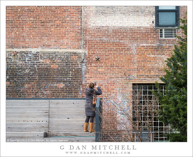 Woman Photographing Brick Wall